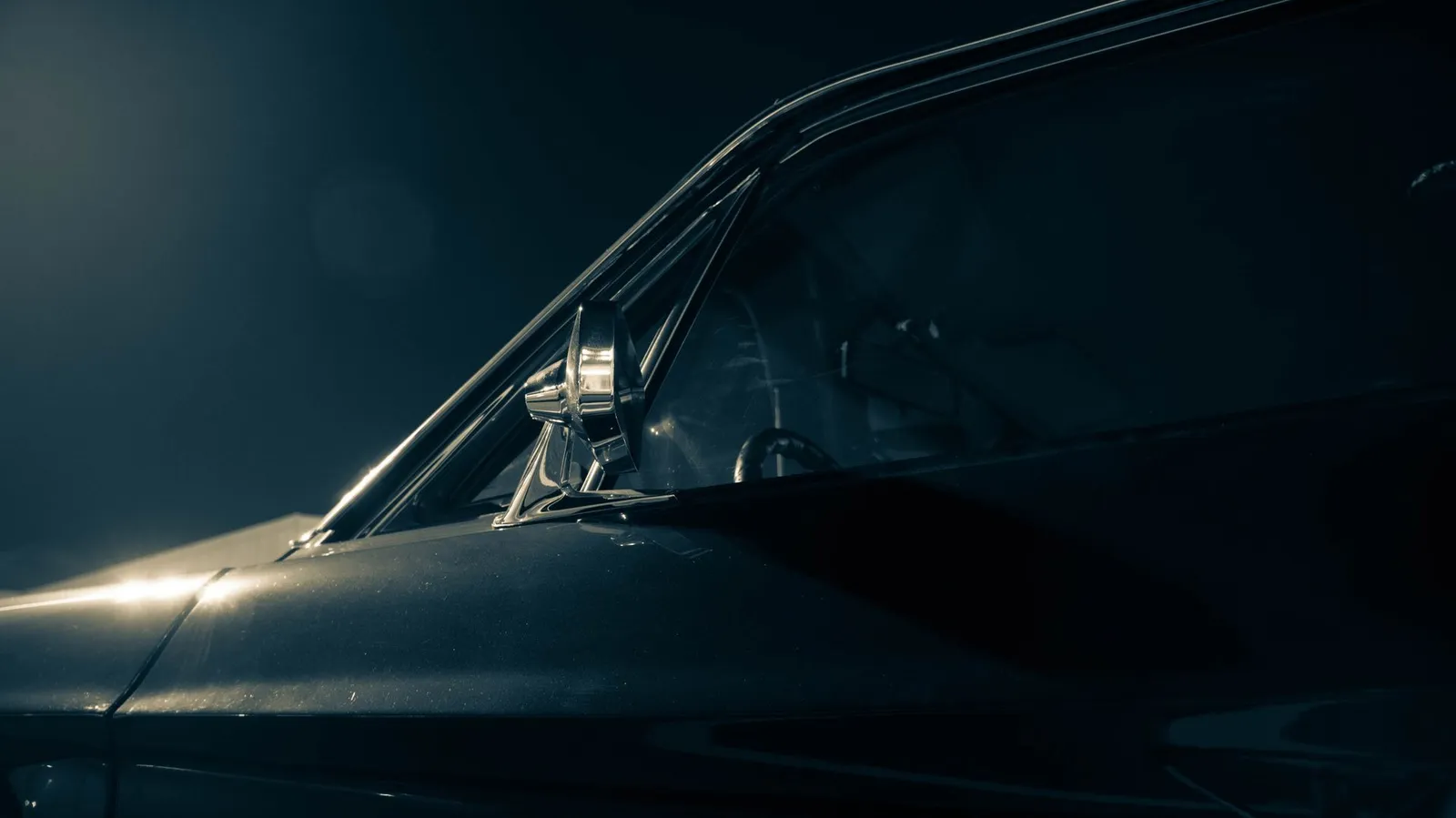 Capô e para-lama escuros com a luz quente do estúdio na pintura e o retrovisor cromado